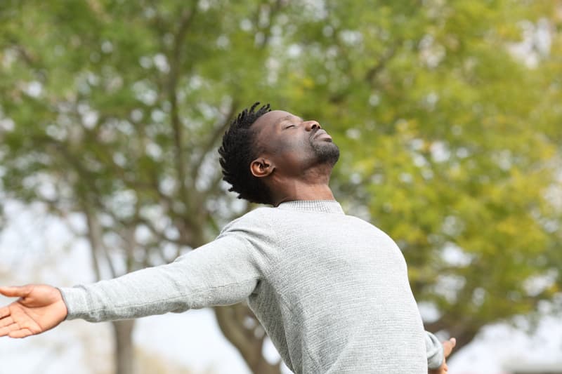 Black-man-breathing-fresh-air-stretching-arms-in-a-park