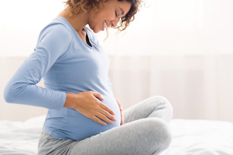 Happy pregnant woman touching her belly