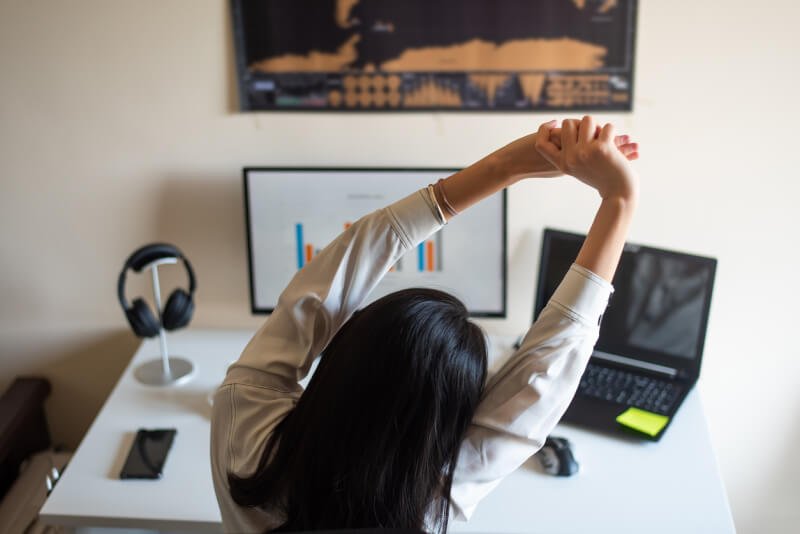 Woman stretching while working from a home office